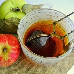 Чай из листьев яблони в прозрачной чашке, рядом лежат яблоки