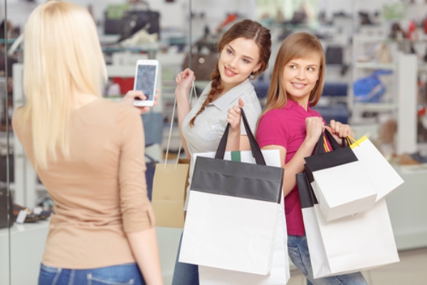Три красивые девуши со смартфоном делают покупки
