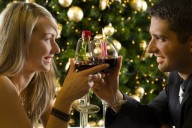 Романтическая пара влюбленный с бокалами шампанского ужинает на фоне новогодней елки