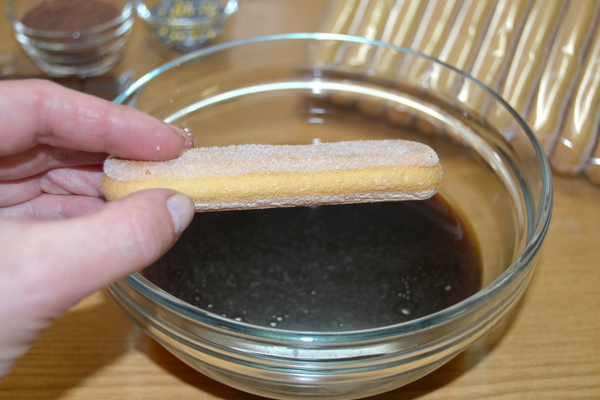 Бисквитные палочки окунают в кофе эспрессо и после этого кладут в форму для торта       