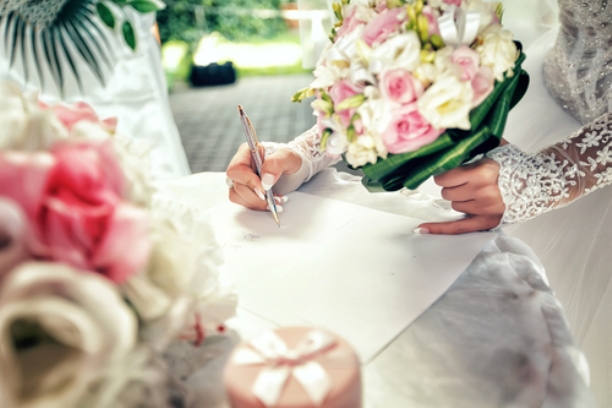 Bride signs up document on civil wedding ceremony.
